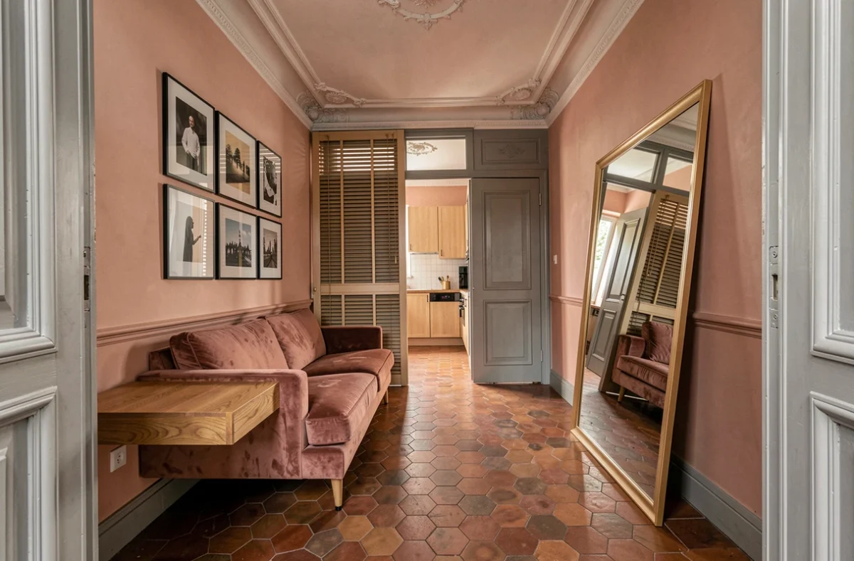 Petit salon parisien optimisé avec miroir, mobilier multifonction et galerie de cadres muraux pour agrandir visuellement l'espace